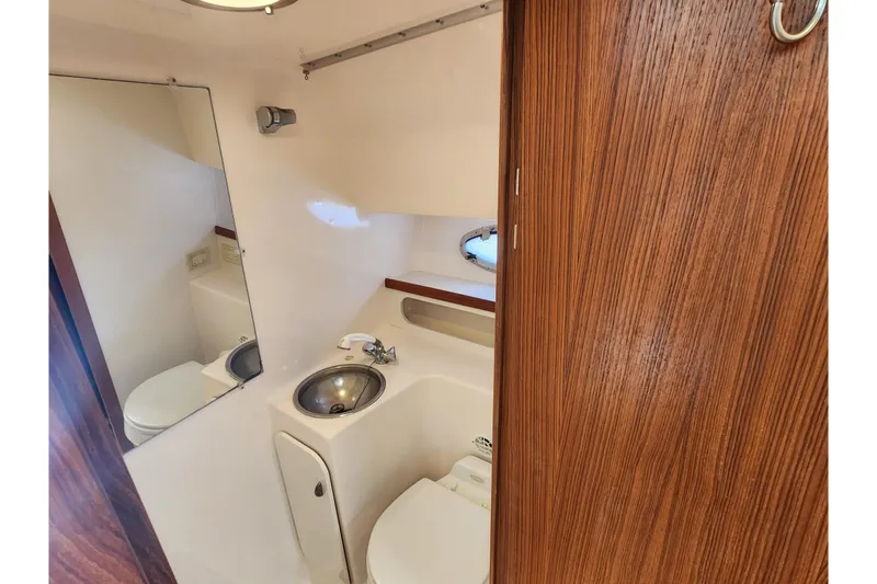 Slide: The Image of 2003 Tiara Yachts 3100 Open LE bathroom with sink, toilet, and wooden accents. - 38