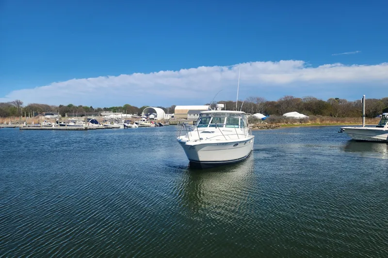 Slide: The Image of 2003 Tiara Yachts 3100 Open LE cruising in a serene marina setting. - 48