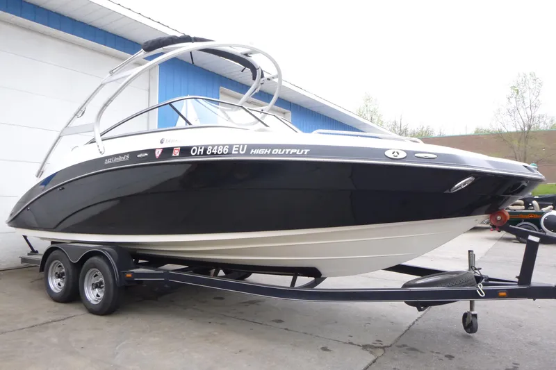 The Image of 2011 Yamaha Boats 242 Limited S on trailer, sleek black design, parked outdoors. - 1