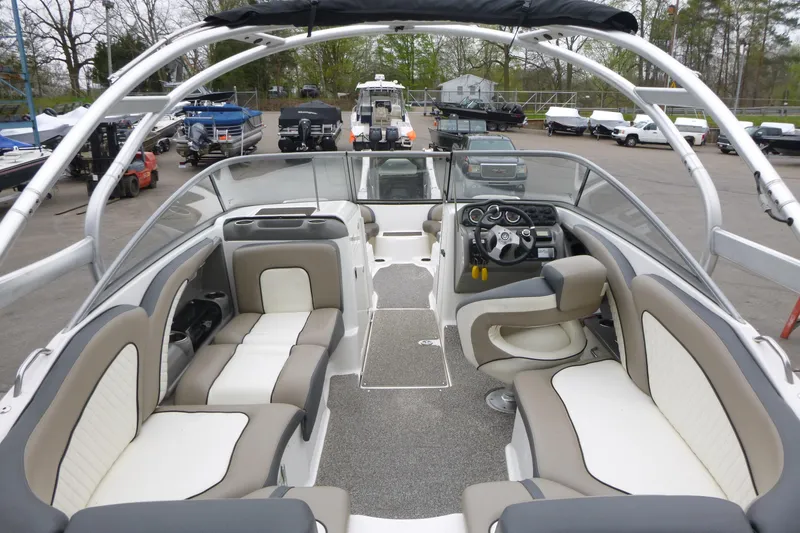 Slide: The Image of 2011 Yamaha Boats 242 Limited S interior with seating and steering wheel, parked in marina. - 6