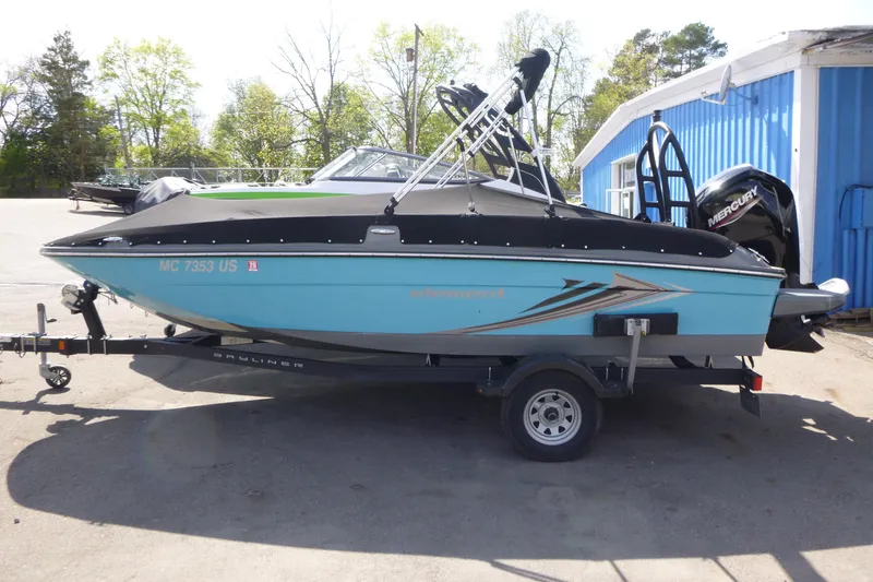 The Image of 2022 Bayliner Element E18 boat on trailer, parked outdoors near blue building. - 1
