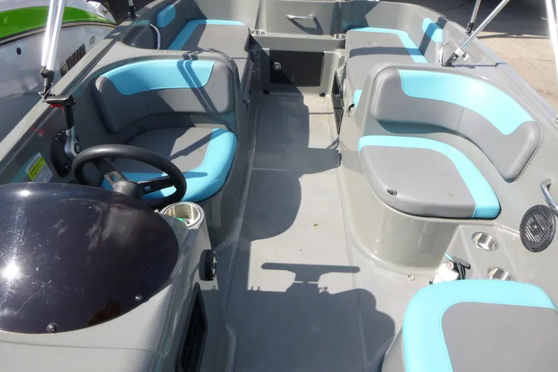Slide: The Image of 2022 Bayliner Element E18 boat interior with gray and blue seating, steering wheel, and cup holders. - 9