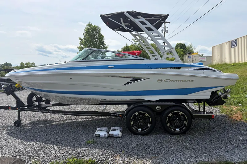 The Image of 2025 Crownline 220 SS boat on trailer, featuring sleek blue and white design. - 0