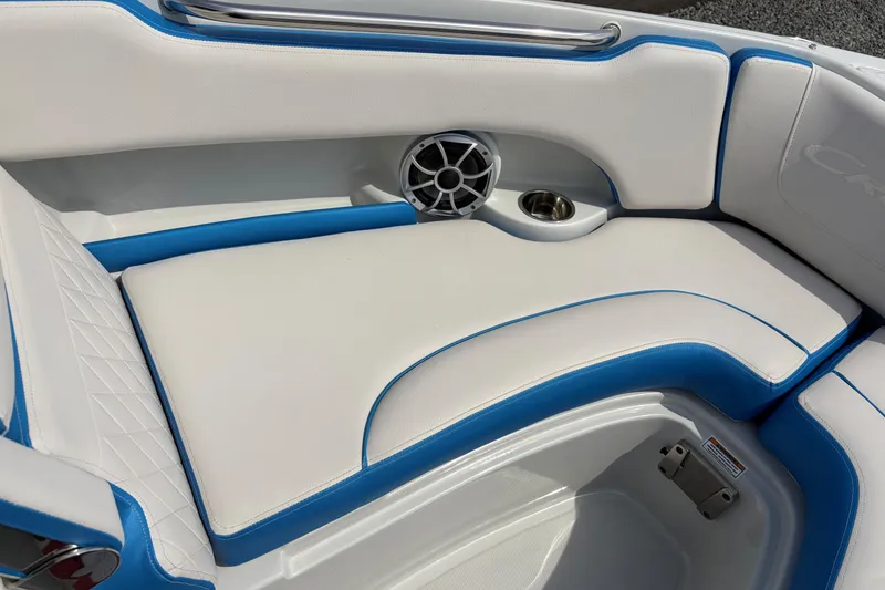 Slide: The Image of 2025 Crownline 220 SS boat interior with white and blue seating, speaker, and cup holder. - 10