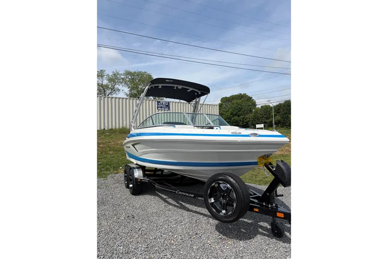 Slide: The Image of 2025 Crownline 220 SS boat on trailer, displayed outdoors with blue sky background. - 4