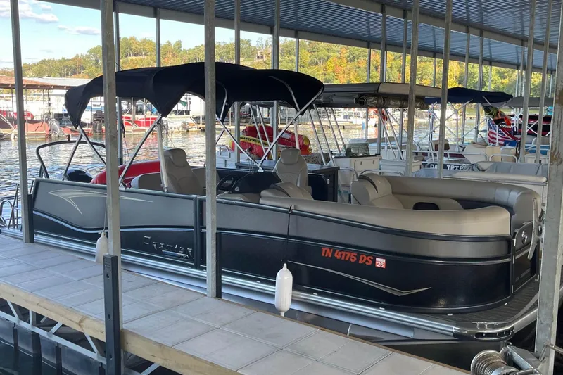 The Image of 2023 Premier Sunsation pontoon boat docked in a marina under a covered structure. - 0