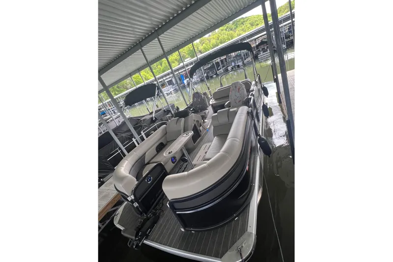 Slide: The Image of 2023 Premier Sunsation pontoon boat docked under a covered marina. - 2