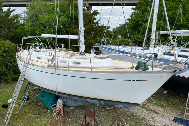 The Image of 1979 Fuji 40 sailboat on land, surrounded by greenery and other boats. - 0
