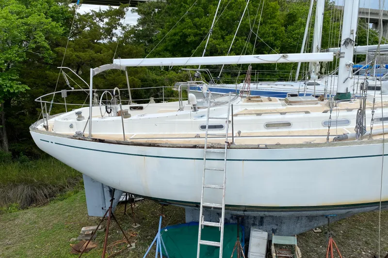 Slide: The Image of Sailboat on land, Fuji 40 model from 1979, with ladder and trees in background. - 2