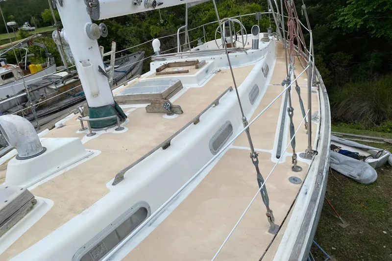 Slide: The Image of 1979 Fuji 40 sailboat deck with rigging, docked near lush greenery. - 24