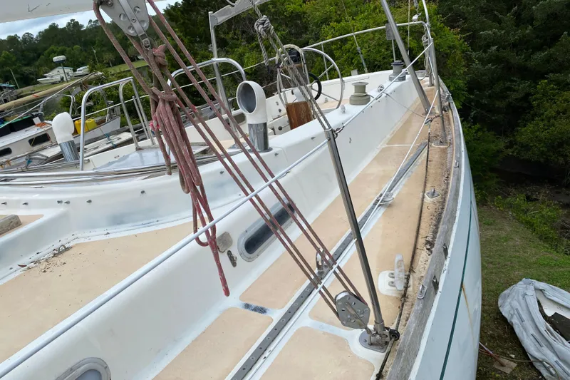 Slide: The Image of 1979 Fuji 40 sailboat deck with rigging, surrounded by lush greenery. - 27