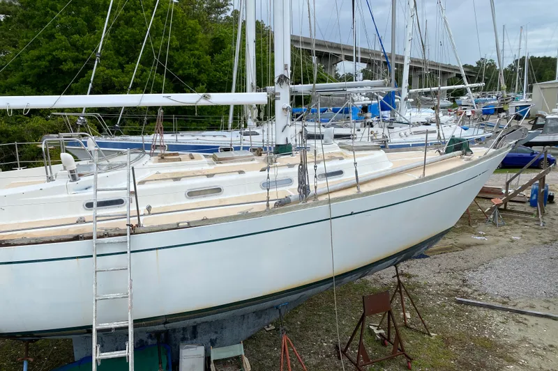 Slide: The Image of 1979 Fuji 40 sailboat on dry dock, surrounded by other boats, with a ladder leaning against it. - 3