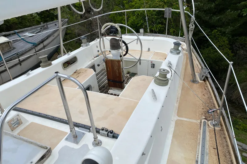 Slide: The Image of 1979 Fuji 40 sailboat cockpit with steering wheel and winches, surrounded by lush greenery. - 30