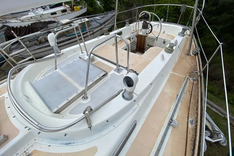 Slide: The Image of 1979 Fuji 40 sailboat deck with steering wheel and railing, docked among other boats. - 31