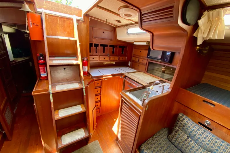 Slide: The Image of Interior of a 1979 Fuji 40 sailboat with wooden cabinetry and compact kitchen area. - 39