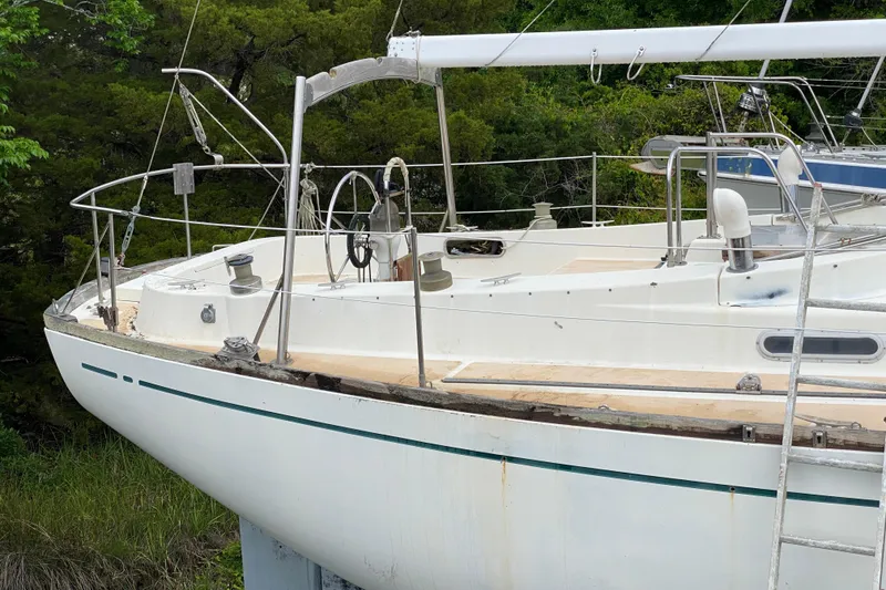 Slide: The Image of 1979 Fuji 40 sailboat with white deck, docked near lush greenery. - 4