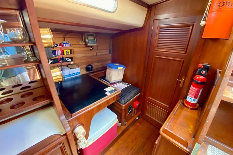 Slide: The Image of Cozy 1979 Fuji 40 yacht interior with wooden cabinetry, navigation equipment, and safety gear. - 44