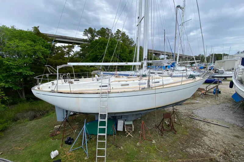 Slide: The Image of 1979 Fuji 40 sailboat on land with ladder, surrounded by trees and other boats. - 6