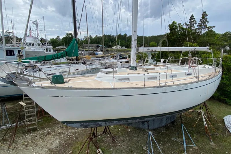 Slide: The Image of 1979 Fuji 40 sailboat on stands, surrounded by other boats, under cloudy sky. - 8
