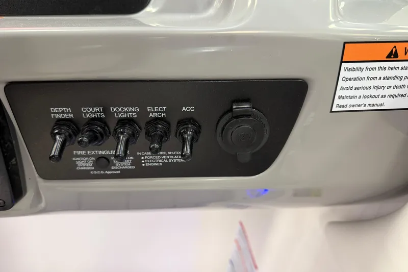 Slide: The Image of Control panel of 2025 Chaparral 21 SSi OB boat with switches and warning label. - 13