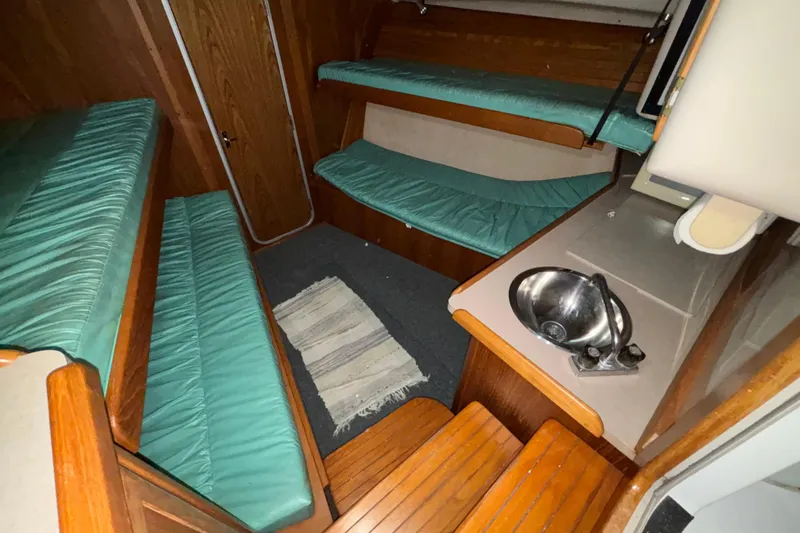 Slide: The Image of 1995 Luhrs 29 Open cabin interior with teal cushions and compact sink area. - 26