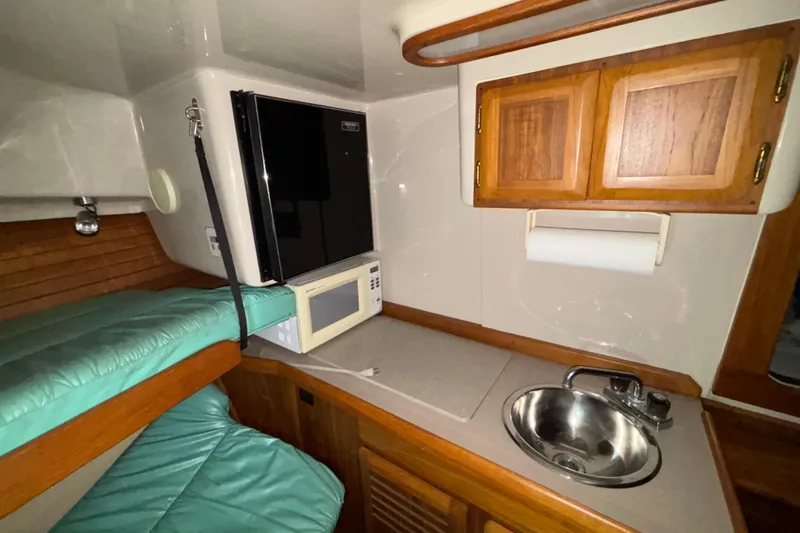 Slide: The Image of 1995 Luhrs 29 Open cabin interior with kitchenette, microwave, sink, and wooden cabinets. - 27