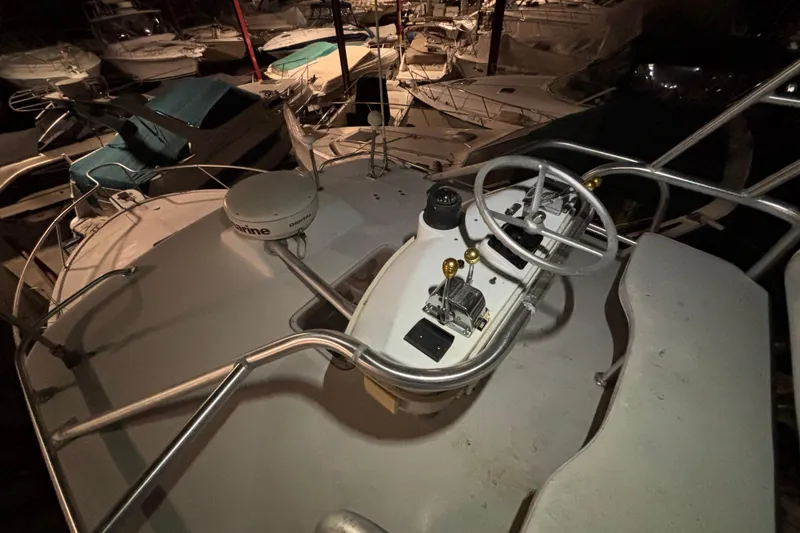 Slide: The Image of 1995 Luhrs 29 Open boat helm with steering wheel and controls, docked among other boats. - 37