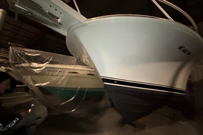 Slide: The Image of 1995 Luhrs 29 Open boat in storage, partially covered, with visible hull and bow. - 40