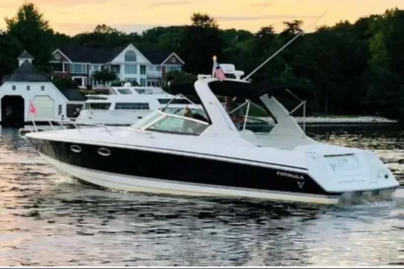 The Image of 2005 Formula 330 Sun Sport boat cruising on a scenic lake at sunset. - 0