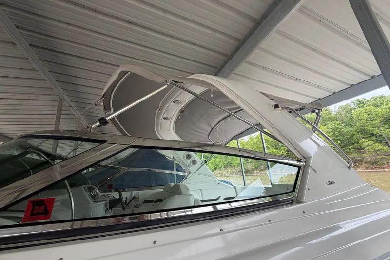 Slide: The Image of 2005 Formula 330 Sun Sport boat under a metal canopy, docked near a wooded shoreline. - 7