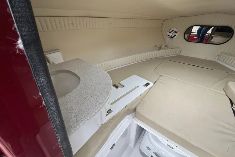 Slide: The Image of Interior cabin of 2026 Stingray 23 OCX boat with beige upholstery and compact amenities. - 23
