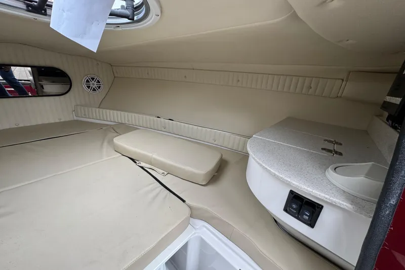 Slide: The Image of 2026 Stingray 23 OCX cabin interior with beige seating and compact kitchenette. - 24