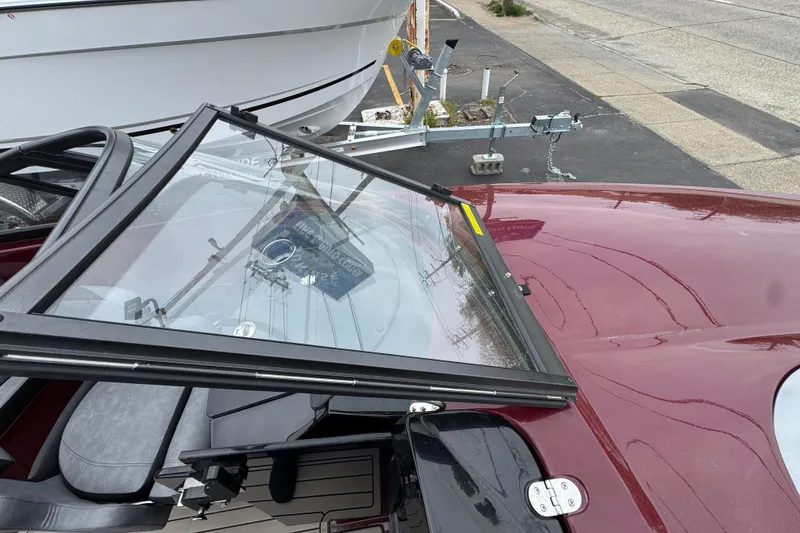 Slide: The Image of 2026 Stingray 23 OCX boat with maroon exterior and windshield, parked on a trailer. - 27