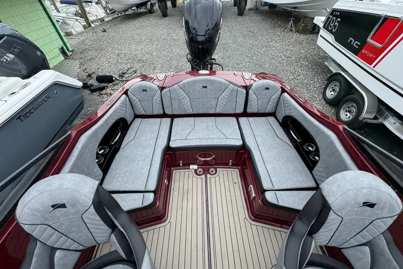 Slide: The Image of 2026 Stingray 23 OCX boat interior with gray seating and red accents, docked outdoors. - 32