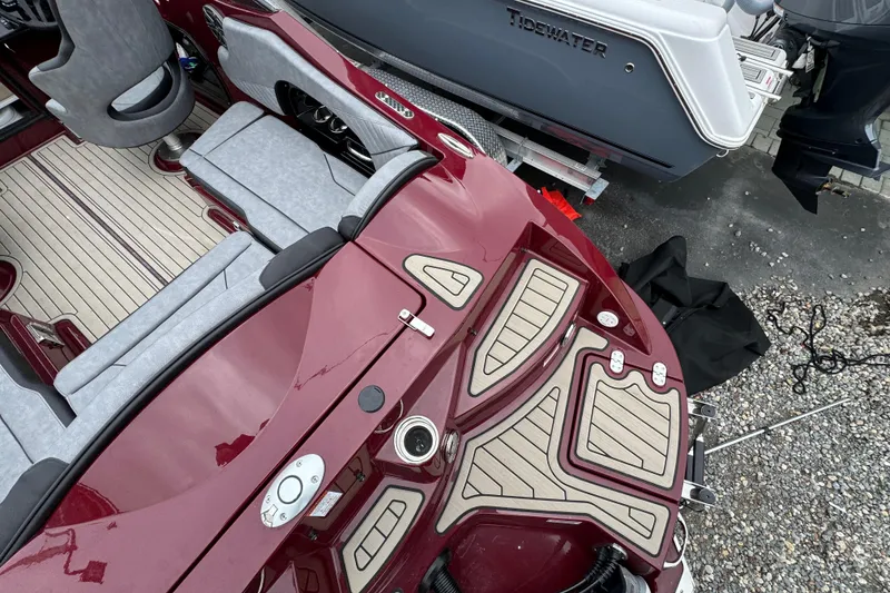 Slide: The Image of 2026 Stingray 23 OCX boat interior with maroon and gray seating, docked beside another vessel. - 36