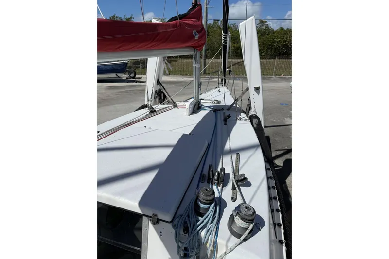 Slide: The Image of 1990 Corsair F 27 sailboat deck with ropes and winches, docked outdoors. - 11