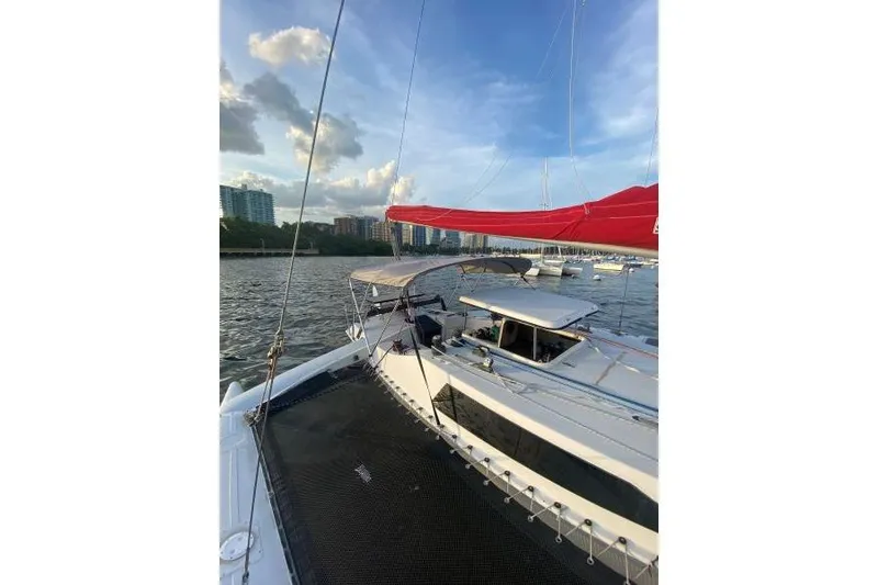 Slide: The Image of 1990 Corsair F 27 sailboat on water, with red sail and city skyline background. - 3