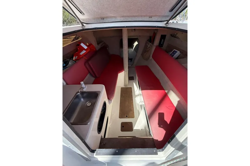 Slide: The Image of Interior of 1990 Corsair F 27 sailboat with red seating and compact kitchenette. - 4