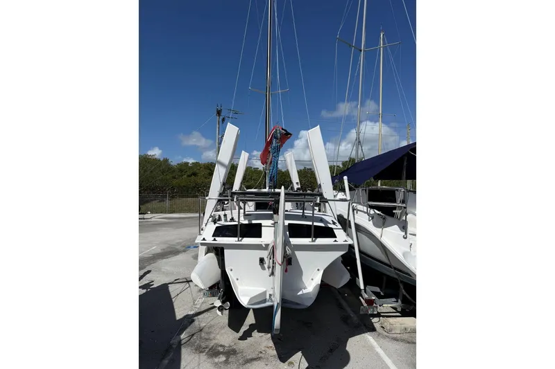 Slide: The Image of 1990 Corsair F 27 sailboat on trailer, parked outdoors under clear blue sky. - 9