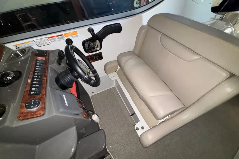 Slide: The Image of 2014 Rinker 290 Express Cruiser helm with beige seating and control panel. - 34