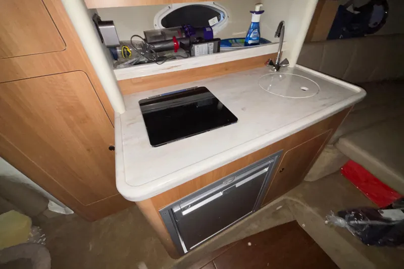 Slide: The Image of 2014 Rinker 290 Express Cruiser interior kitchenette with sink, stove, and storage. - 39