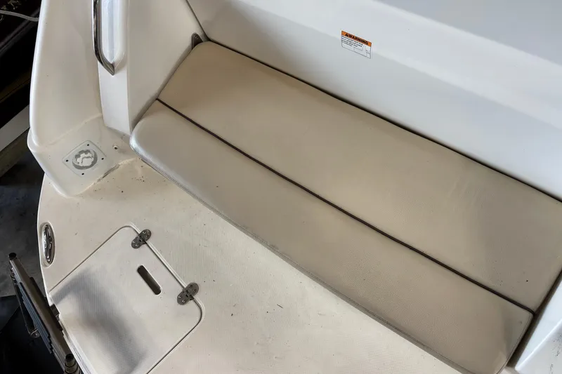 Slide: The Image of 2014 Rinker 290 Express Cruiser seating area with beige cushions and storage compartment. - 47