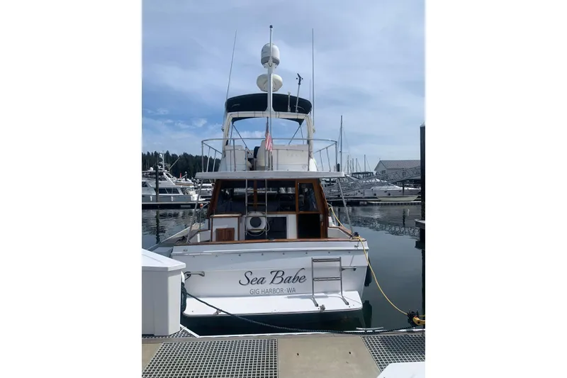 Slide: The Image of 1991 Bayliner 3288 Motoryacht docked at marina, rear view with "Sea Babe" name. - 3
