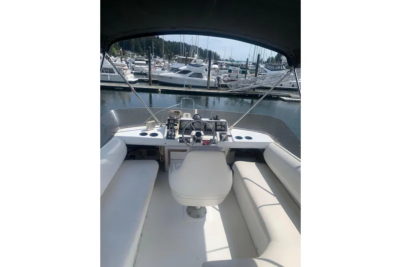 Slide: The Image of 1991 Bayliner 3288 Motoryacht helm view at marina, showcasing steering and seating area. - 4