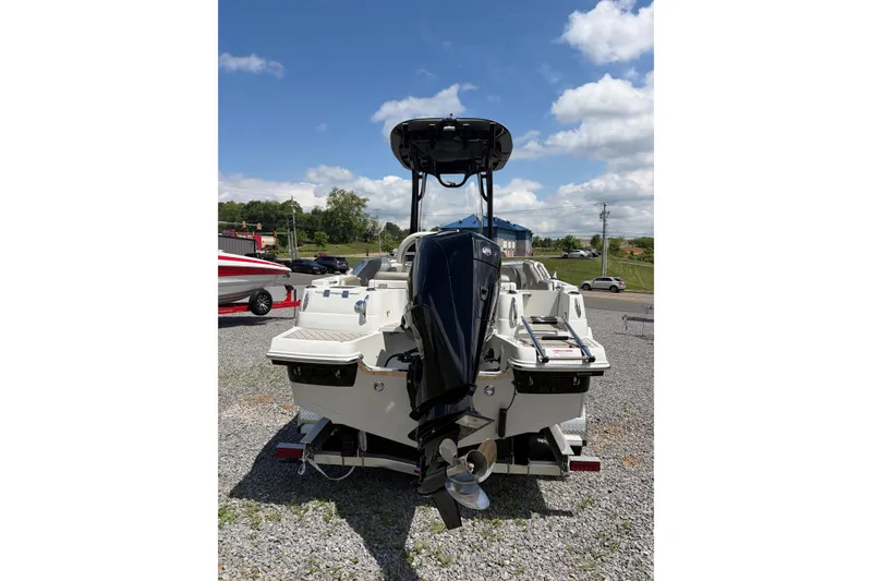 Slide: The Image of 2026 Crownline 210 CC Finseeker boat, rear view, parked on gravel under a blue sky. - 17