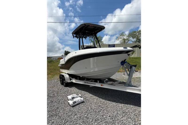 Slide: The Image of 2026 Crownline 210 CC Finseeker boat on trailer, parked outdoors under a blue sky. - 18