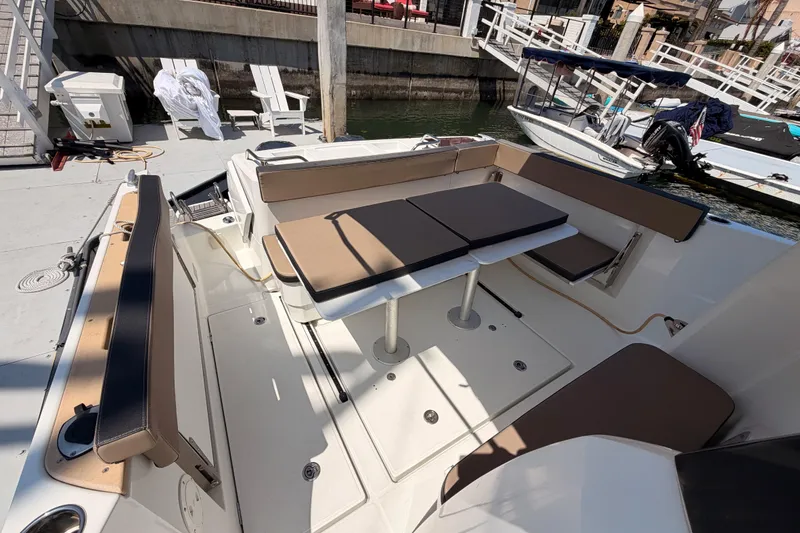 Slide: The Image of 2017 Jeanneau Merry Fisher 855 Marlin boat interior with seating and table at dock. - 12
