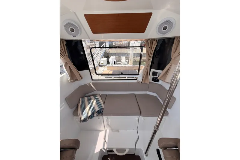 Slide: The Image of Interior of 2017 Jeanneau Merry Fisher 855 Marlin, featuring cushioned seating and window view. - 32