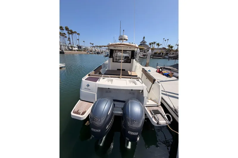 Slide: The Image of 2017 Jeanneau Merry Fisher 855 Marlin docked, featuring dual outboard engines. - 6