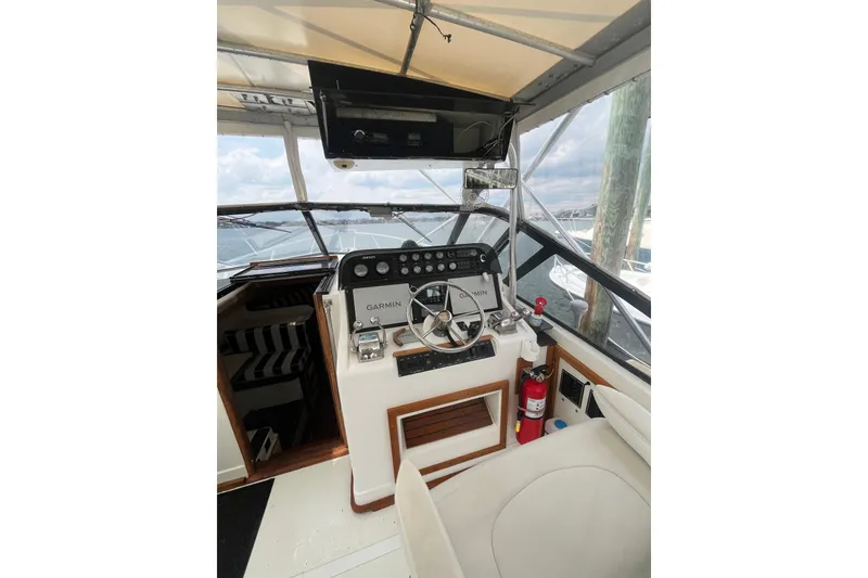 Slide: The Image of 1989 Blackfin 31 Combi boat cockpit with steering wheel, Garmin controls, and fire extinguisher. - 8